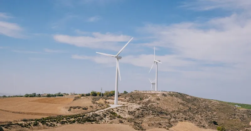 Wind turbines generating renewable energy on a rural landscape under a clear blue sky.
