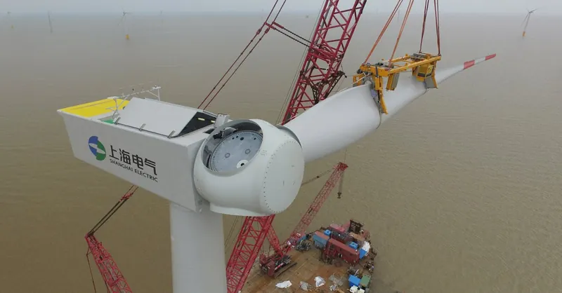 Aerial view of a wind turbine being installed over the sea, showcasing renewable energy construction.