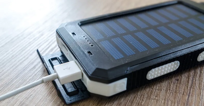 A close-up of a solar charger with a USB connection on a wooden surface, showcasing modern technology.