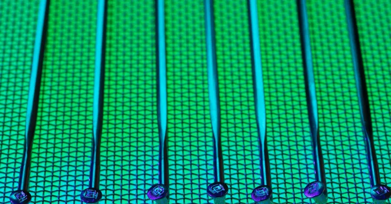 Vivid and detailed close-up of a patterned silicon wafer with vibrant green and blue colors.