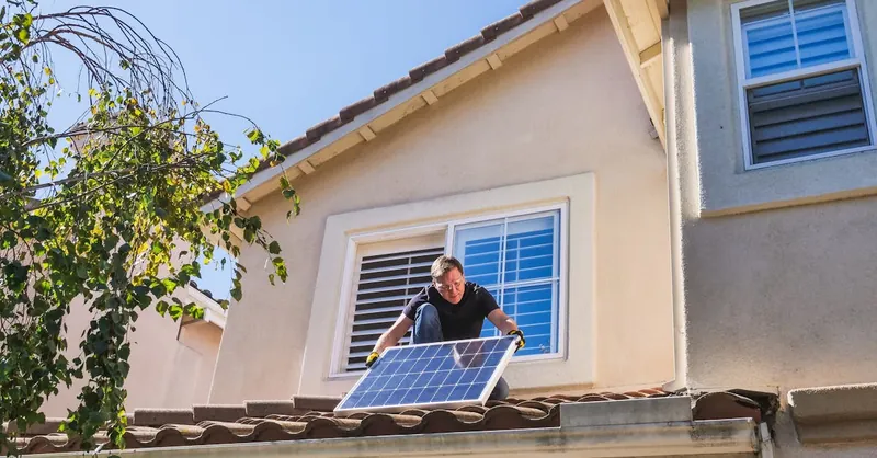 Solar technician installing photovoltaic panels on a sunny rooftop.
