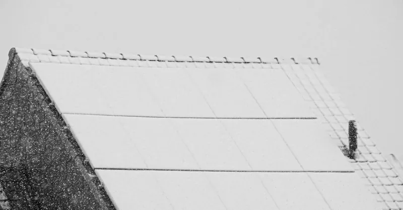 Snow-covered solar panels on a rooftop in winter, highlighting renewable energy challenges in cold climates.