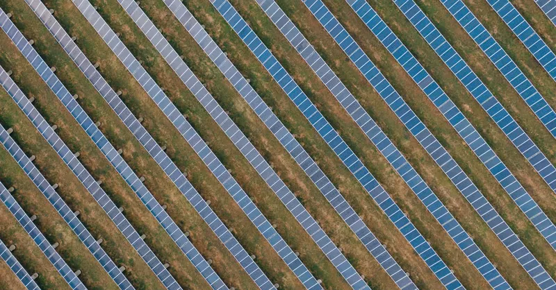 Aerial view of uniform solar panels in a green field, showcasing sustainable energy.