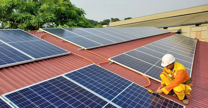 A solar technician performs maintenance on rooftop solar panels enhancing energy efficiency.