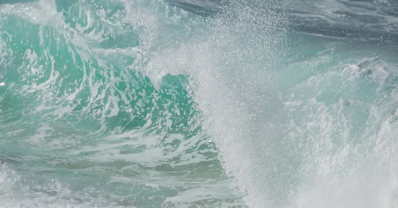 Close-up of teal ocean waves crashing, capturing the dynamic energy of the sea in summer.