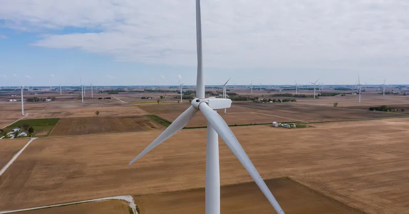 Aerial view of wind turbines scattered across vast farmland, illustrating renewable energy in Indiana.