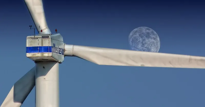 Wind turbine blades with moon backdrop, highlighting renewable energy aesthetics.