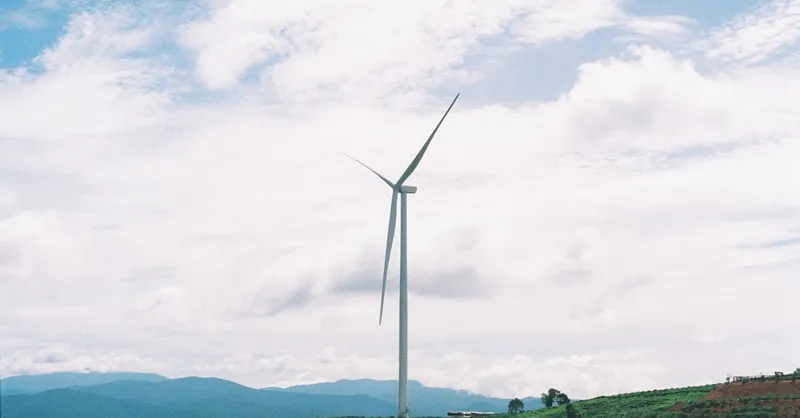 A wind turbine in a vast, green landscape, symbolizing renewable energy and sustainability.