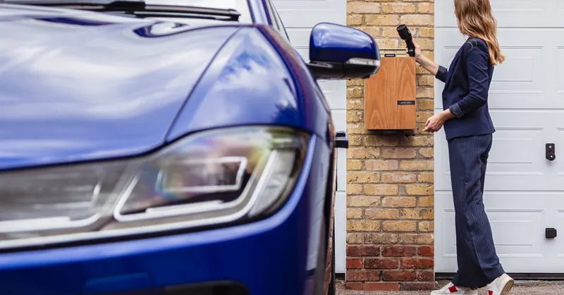 Woman charging an electric car at a home station, promoting sustainability.
